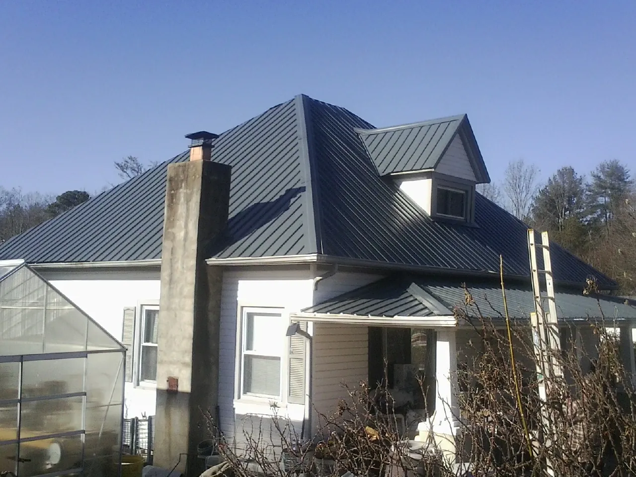 Dark blue standing seam metal roof on a white farmhouse with dormer — Slate & Tile Roof Repair by Roofing Brothers in Zeigler