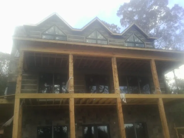 Dormers and porch framing on a large log home under construction — Roof Coating work by our crew in Zeigler