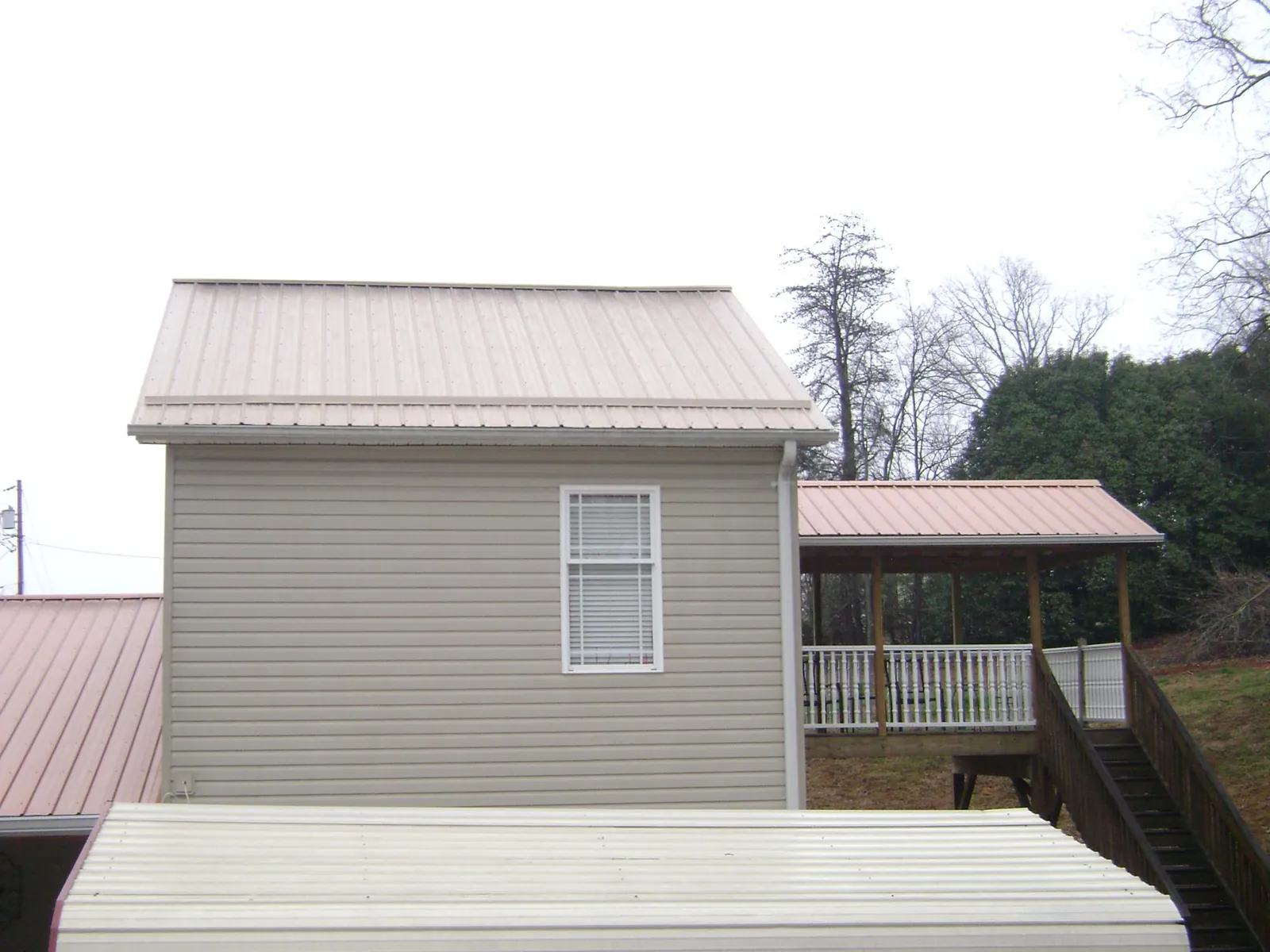 Tan metal roofs on a two story addition and attached porch, from a Roof Replacement job in Zeigler