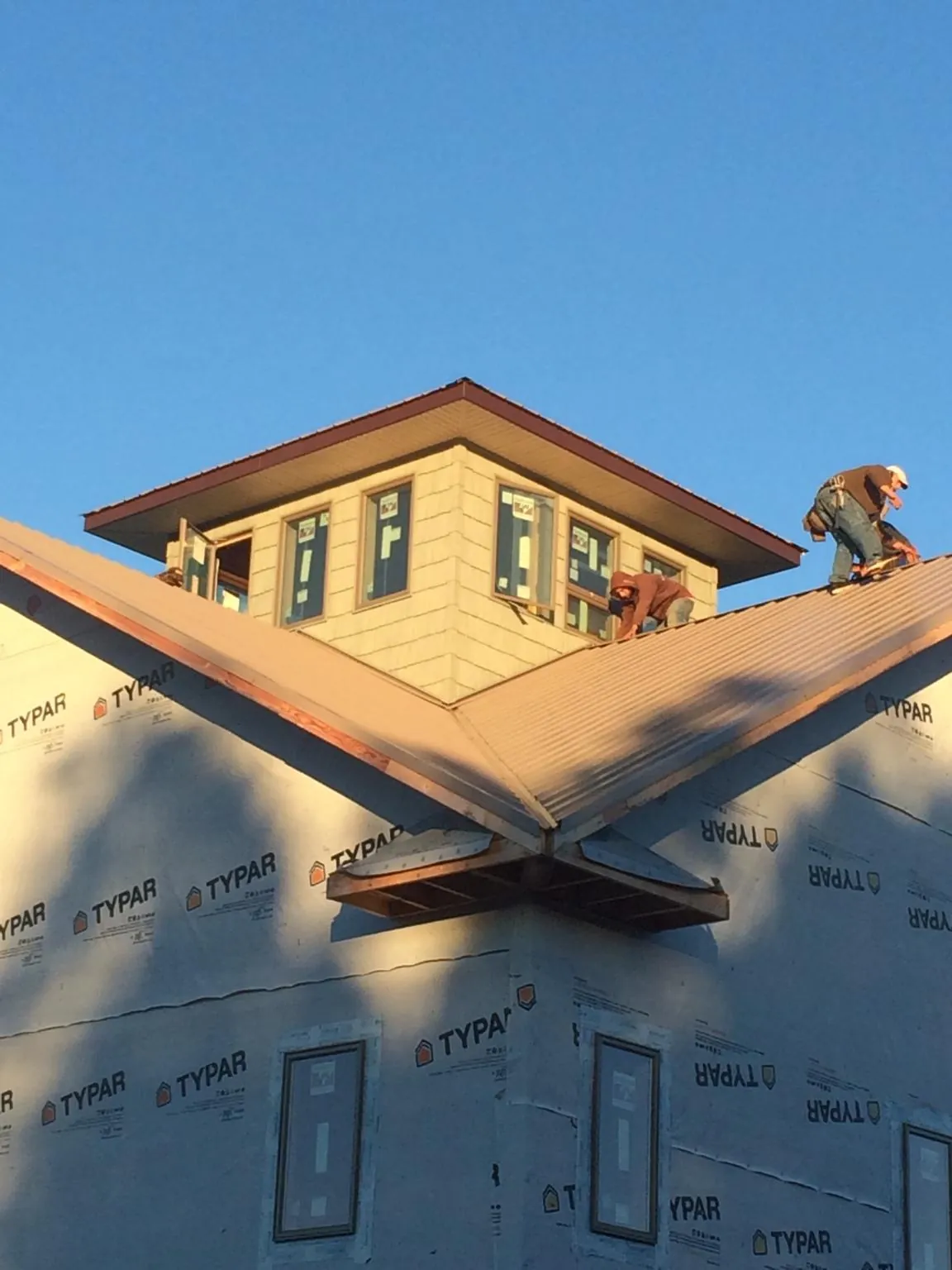 Roofers working around a rooftop cupola on a new metal roof at sunset — Roof Waterproofing in Zeigler by Roofing Brothers
